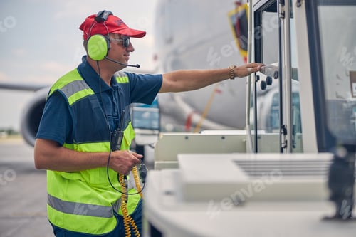 Preview: Airport worker standing in front of a pushback tug