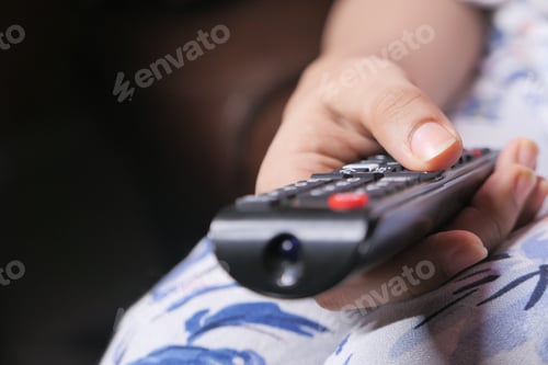Preview: close up of women hand holding tv remote.