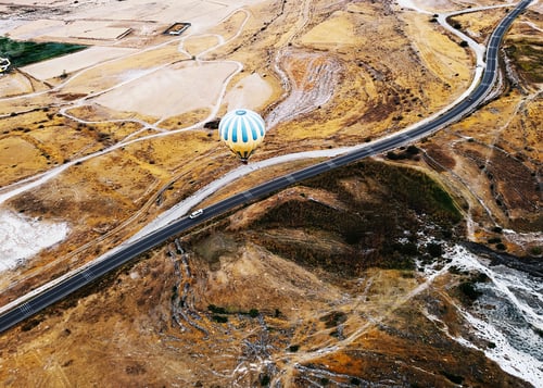 Preview: Hot air balloon over the countryside road with a white car