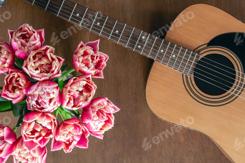 Preview: Bouquet of pink tulips and acoustic guitar on a wooden background, top view.