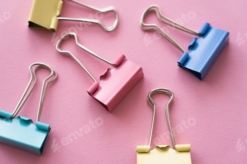 Preview: close up of colorful pastel fold back clips on pink