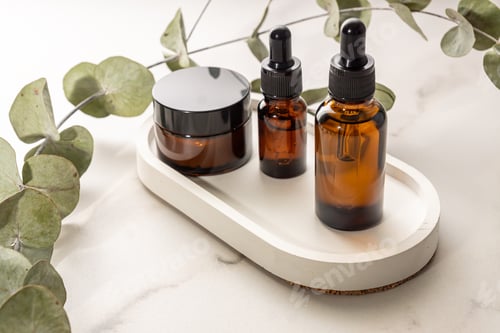 Preview: Set of natral organic cruelty free cosmetics in dark glass package on concrete tray with dry branch