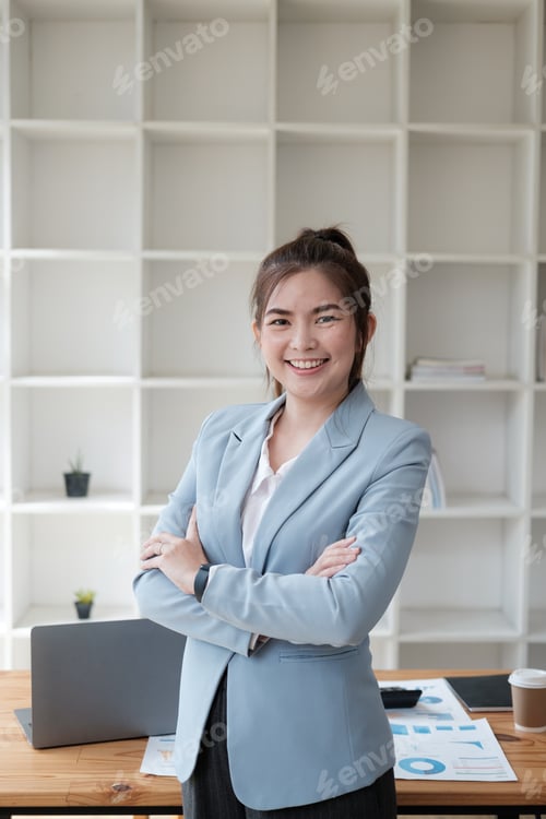 Preview: Beautiful and confident Asian businesswoman standing in her office room with her arms crossed.