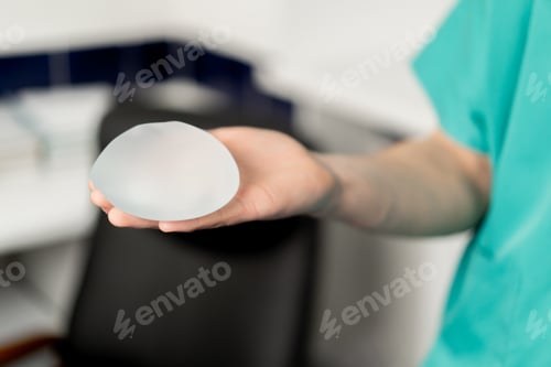 Preview: close-up in a plastic surgery clinic a doctor holds one implant in his hand