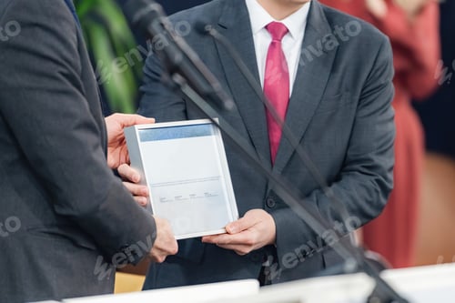 Preview: Speakers presenting a framed certificate at a media conference highlight