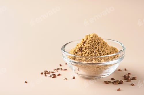 Preview: Flax fiber. Ground flaxseeds in glass bowl soluble fiber supplement for intestinal on a beige backgr