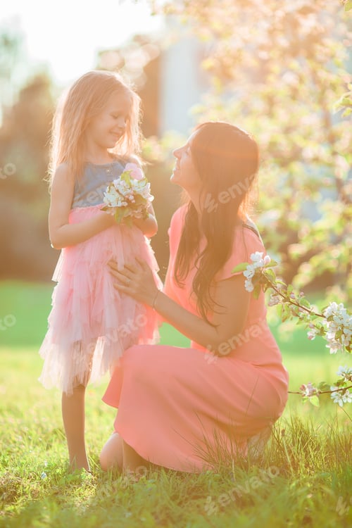 Preview: Adorable little girl with young mother in blooming cherry garden on spring day