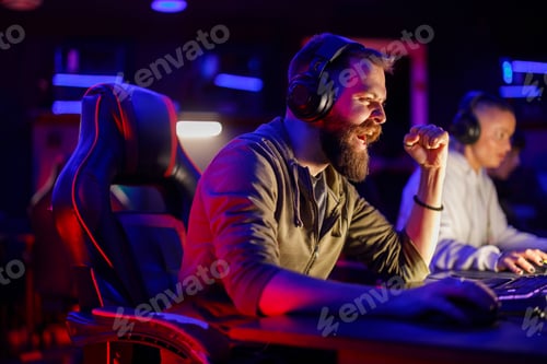 Preview: Pro bearded male gamer celebrating victory while playing online video games