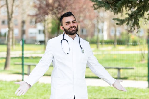 Preview: Portrait of a doctor wearing a lab coat and gloves in a park during daytime
