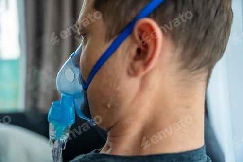 Preview: Unhealthy man wearing nebulizer mask in home. Health, medical equipment and people concept