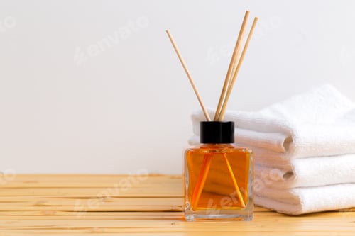 Preview: Fragrant diffuser with sticks beside soft towels on a wooden surface