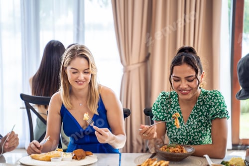Preview: Diverse female friends talking and eating food together in restaurant.