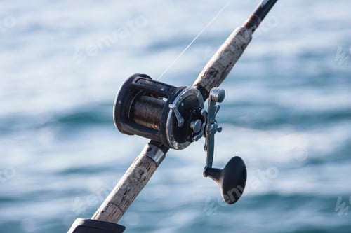 Preview: Closeup of a fishing rod and reel against the backdrop of glistening water.