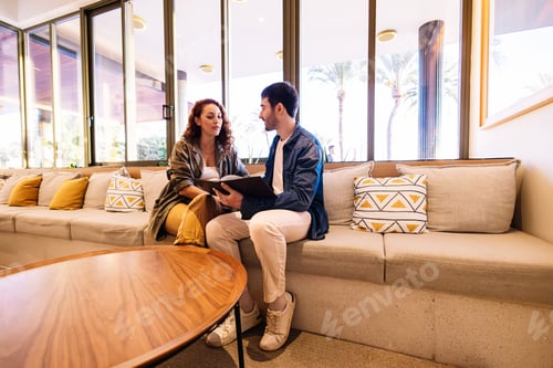 Preview: Couple choosing from menu in stylish hotel lounge. Lifestyle.