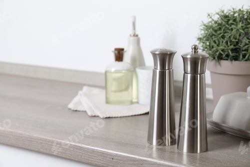Preview: Metal salt and pepper mills on grey wooden counter indoors, closeup. Space for text