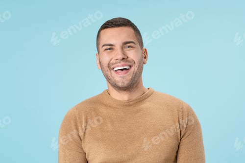 Preview: Laughing handsome guy in sweater isolated on blue background