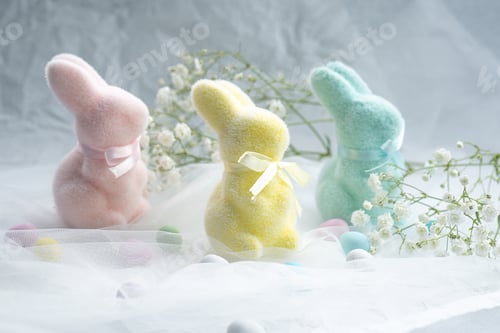 Preview: Colorful plush bunnies surrounded by pastel eggs and flowers in soft light