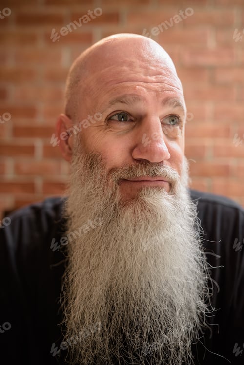 Preview: Portrait of happy mature man smiling and thinking with long gray beard