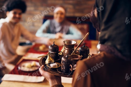 Preview: Close-up of Middle Eastern woman serving traditional Arabic coffee at home