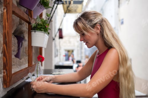 Preview: Beautiful tourist woman in local restaurant outdoor looking at menu, travel lifestyle