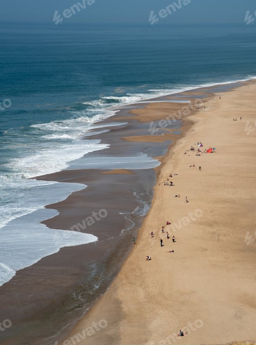 Preview: Tourist people relaxing and sunbathing a sandy tropical beach. Nazare Portugal