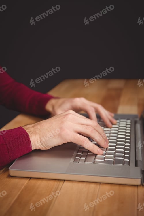 Preview: Cropped image of man working on laptop at desk
