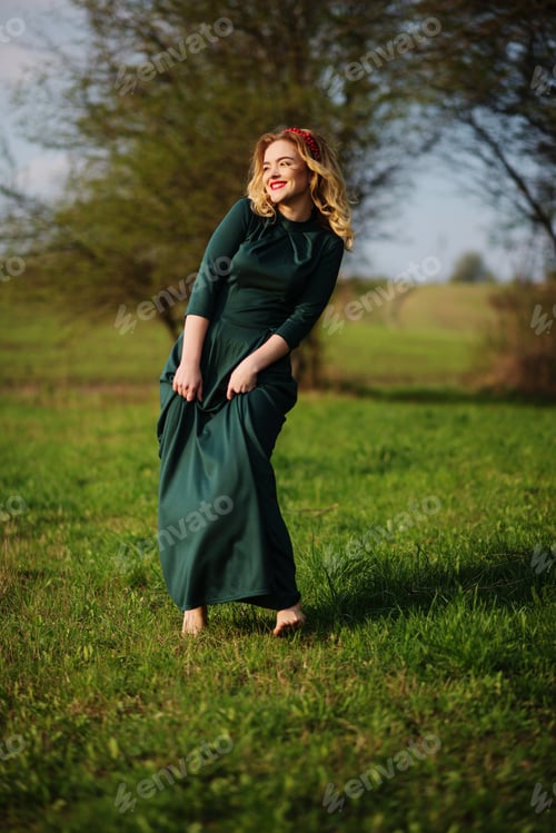 Preview: Yong elegance blonde girl at green dress on the garden in spring.