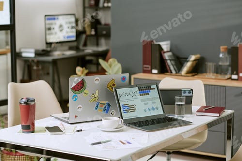 Preview: Modern Office Workspace Featuring Laptops Displaying Data Analytics Graphs