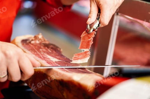 Preview: Professional cutter carving slices from a whole bone-in serrano