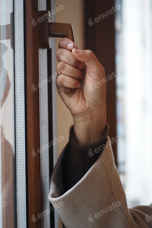 Preview: Hand reaching to open a door in a warm indoor setting