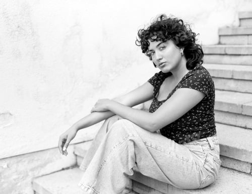 Preview: Young woman sitting on concrete steps, contemplating in monochrome