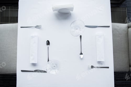 Preview: top view of arranged cutlery and wineglasses on table with white tablecloth in restaurant