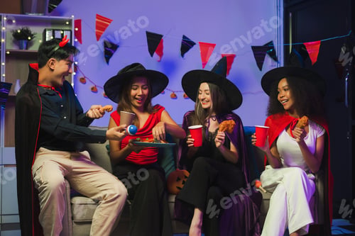 Preview: Dinner and group of people celebrating together at Halloween party.