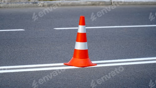 Preview: Traffic cones with orange and white stripes standing on the street during road construction works.