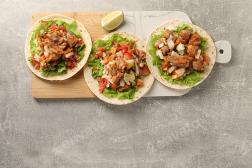 Preview: Delicious tacos with vegetables, meat and lime on grey textured table, top view. Space for text