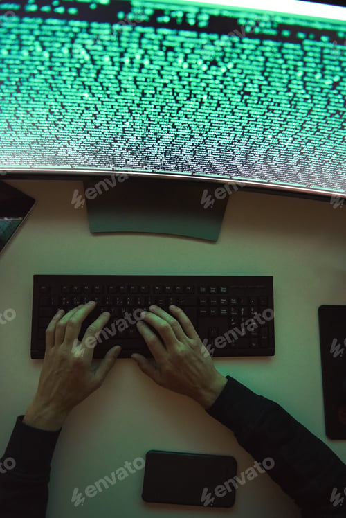 Preview: Data security. Top view of young hacker's hands stealing data while sitting in front of monitor