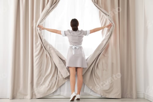 Preview: Young maid opening curtains in hotel room
