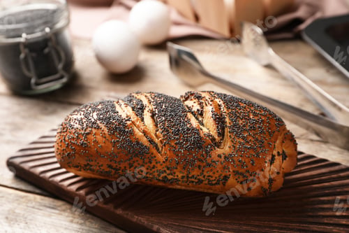 Preview: Board with freshly baked poppy seed roll on table