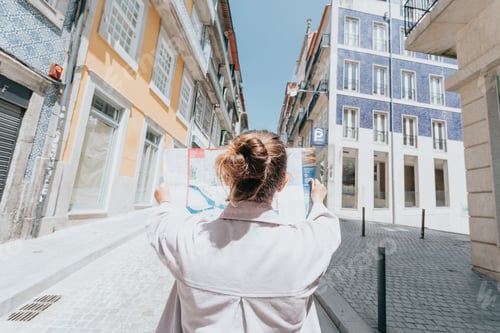 Preview: Young indie woman using a map in the middle of a street in europe, sunny day, summer