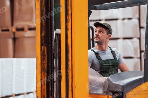 Preview: Young worker in unifrom sits in the forklift in the warehouse