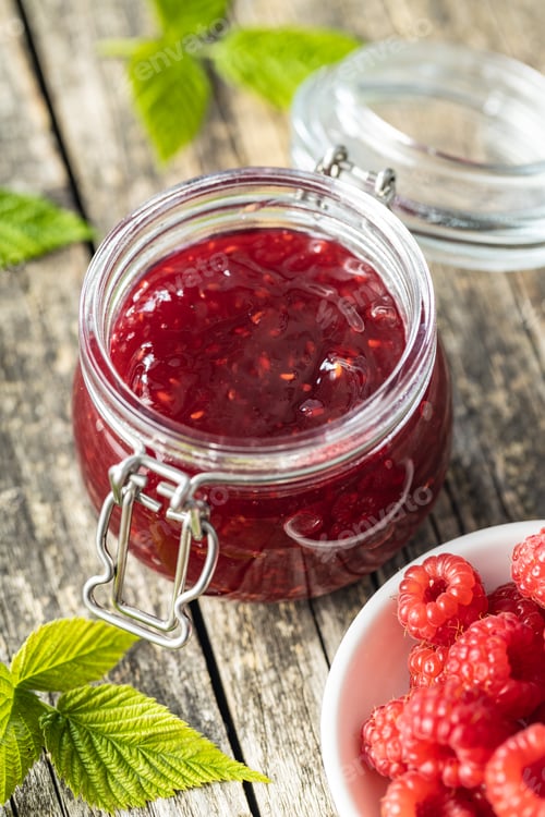 Preview: Red rasberries jam in jar and ripe raspberries.