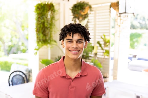 Preview: Portrait of happy biracial man with curly black hair smiling at home in sunny room