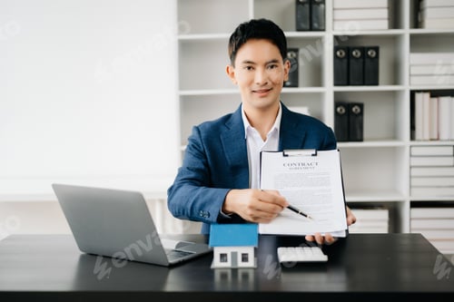 Preview: Young real estate agent worker working with laptop and tablet at table in modern office and small