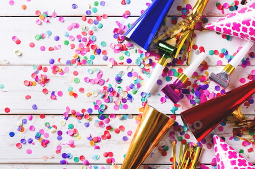 Preview: Colorful party favors scattered on white wooden table