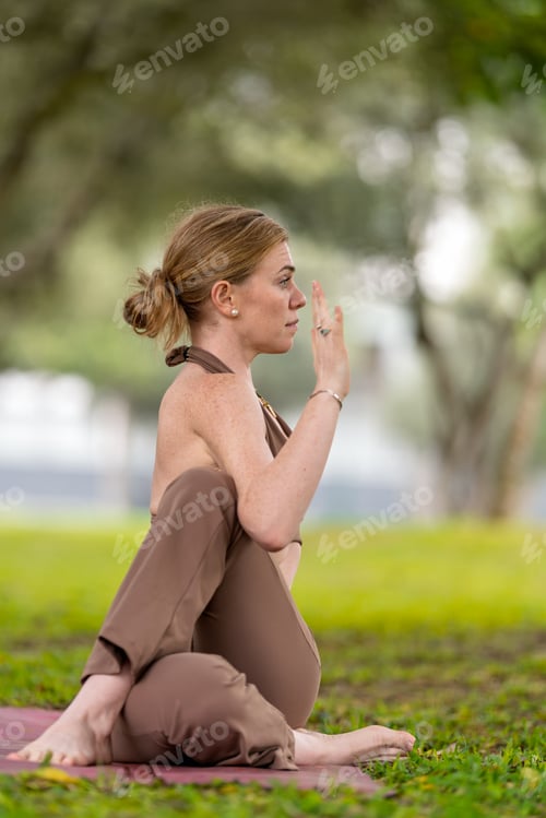 Preview: Yoga instructor performing marichyasana c pose in urban park