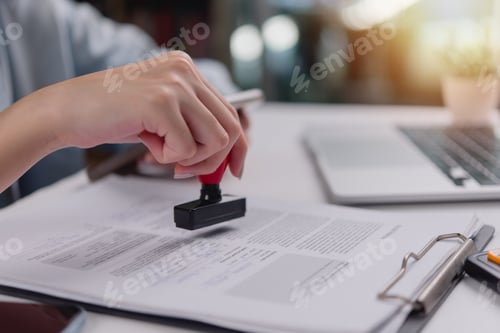 Preview: hand using a red stamp on a legal document, confirmation or validation in administrative work.