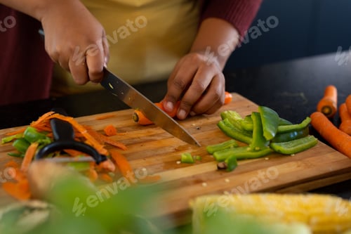 Preview: Midsection of plus size african american woman preparing dinner, chopping vegetables in kitchen
