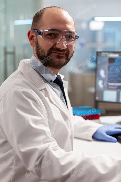 Preview: Microbiology researcher looking at camera in chemical lab