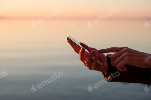 Serene Mobile Technology Use at Sunset by Ocean