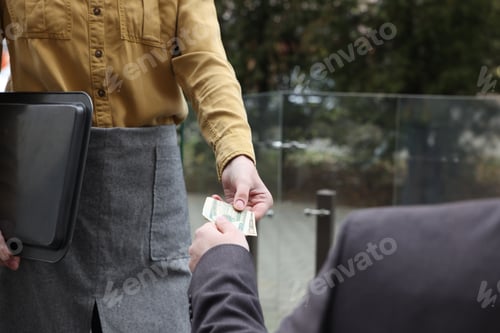 Preview: Client giving tips to waitress in outdoor cafe, closeup